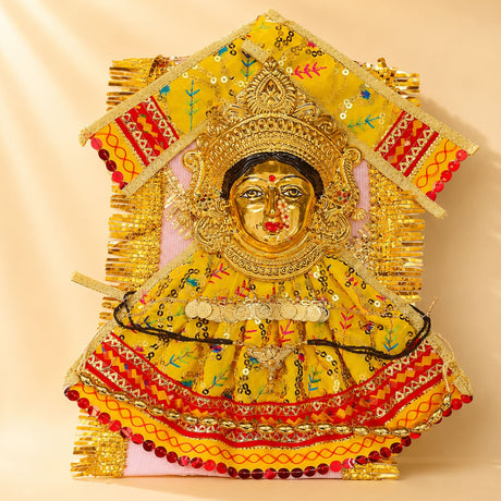 Golden ornate varalaxmi goddess face idol adorned with vibrant yellow and red embroidery dress for navaratri pooja