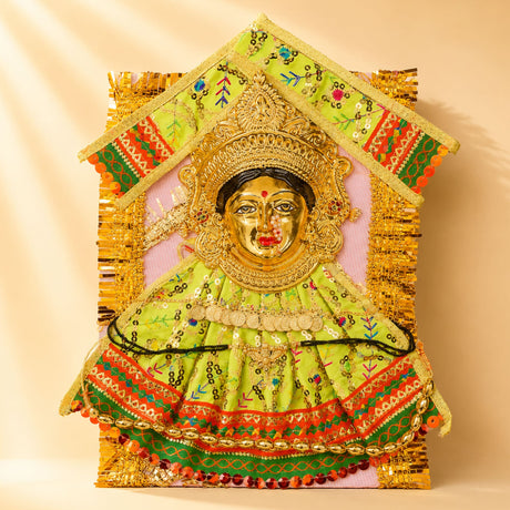 Golden-faced varalaxmi goddess face set adorned in lime green embroidered fabric with sequins and gold coins for pooja rituals