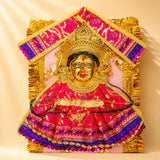 A vibrant pink and gold embroidered Varalaxmi goddess face set with sequins and golden crown for Navaratri pooja