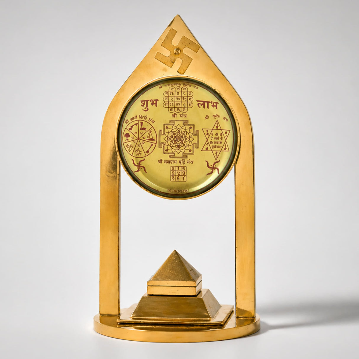 Golden metallic vastu pillar pyramid with ornate sanskrit script geometric symbols and swastika emblem for meditation decor