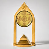Golden metallic vastu pillar pyramid with ornate sanskrit script geometric symbols and swastika emblem for meditation decor