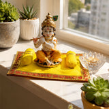 Golden figurine of child playing flute with intricate jewelry seated on ornate yellow velvet pooja mat for laddu gopal rituals