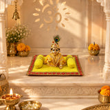 Golden idol of lord krishna with jewelry and peacock feather crown seated on yellow velvet pooja aasan and pillow set