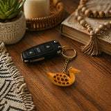 A carved wooden duck keychain with intricate circular patterns and a golden chain in a good luck key holder set