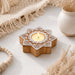Star-shaped wooden block print tea light candle holder with white carved patterns and lit tlight for diwali decoration