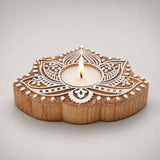 A wooden lotus-shaped tealight holder with intricate white carved patterns and a central candle for Diwali decor