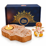 Wooden hand-shaped diya with intricate white carvings and lit candle in Diwali gift hamper for festive celebrations