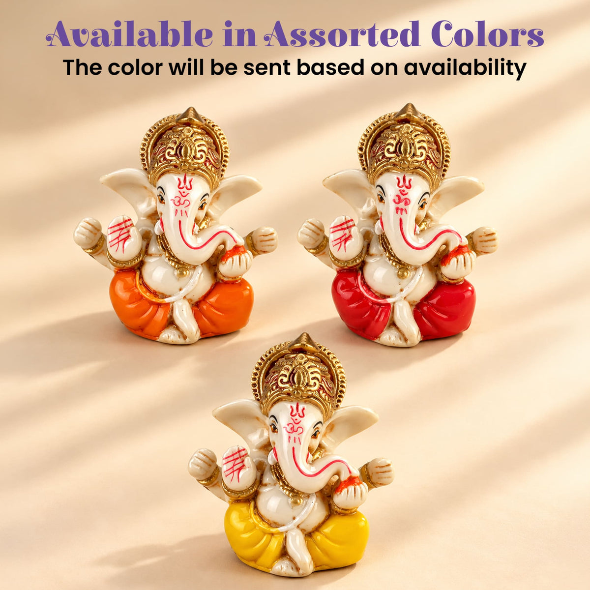 Three miniature ganesha figurines with white bodies and gold crowns in brightly colored robes in a diwali gift hamper