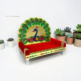 Wooden laddu gopal sinhasan peacock design with vibrant red velvet and gold-embellished intricate feathers for pooja mandir