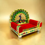 Wooden laddu gopal sinhasan with vibrant red velvet cushion and golden peacock motif for pooja mandir and janmashtami gift