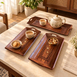 Three hand-painted wooden rectangular serving trays with carved star patterns holding tea set and snacks for home decor