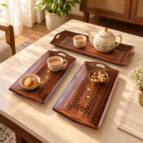 Three hand-painted wooden rectangular serving trays with carved star patterns holding tea set and snacks for home decor