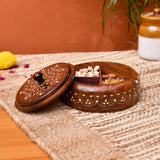 A rich brown wooden round Indian spice box organizer with four compartments and intricate white inlay patterns and black knob handle